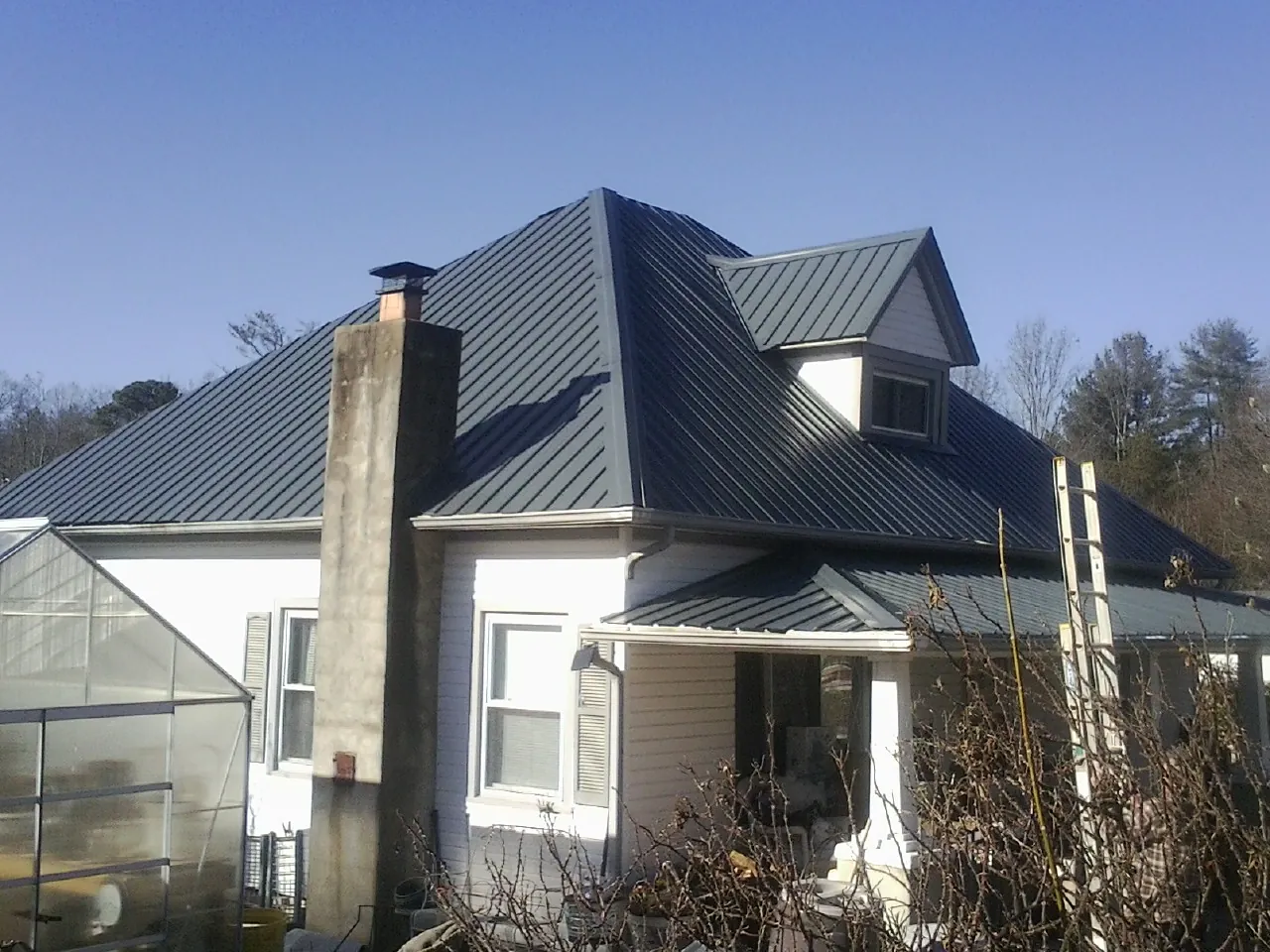 Dark blue standing seam metal roof on a white farmhouse with dormer — Slate & Tile Roof Repair by Roofing Brothers in Cuyahoga Falls