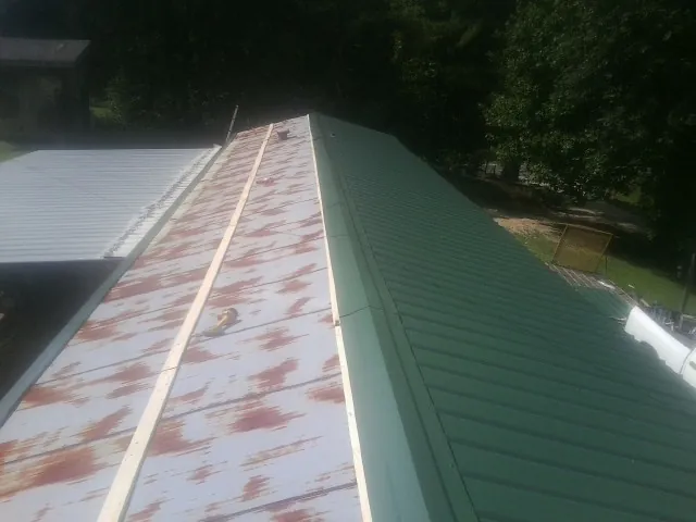 Old rusted panels beside newly installed green metal roofing — Wind Damage Roof Repair by Roofing Brothers in Cuyahoga Falls