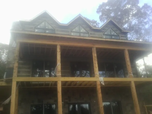 Dormers and porch framing on a large log home under construction — Roof Coating work by our crew in Cuyahoga Falls