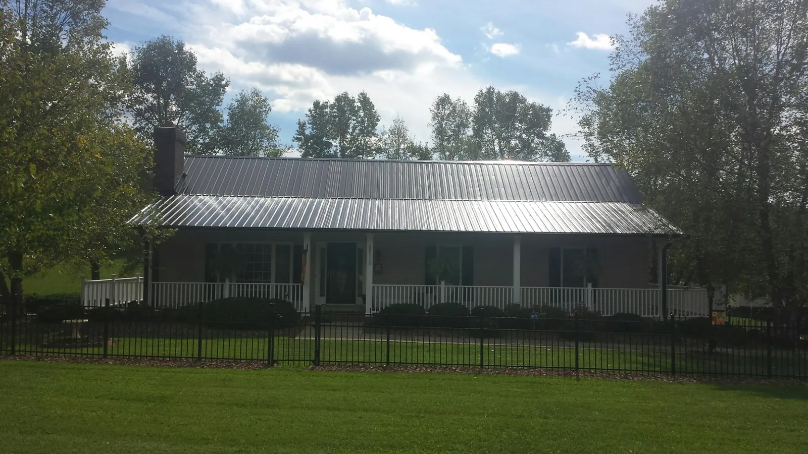 Gray metal roof on a brick ranch with a full width front porch — Gutter Guard Installation work by our crew in Cuyahoga Falls