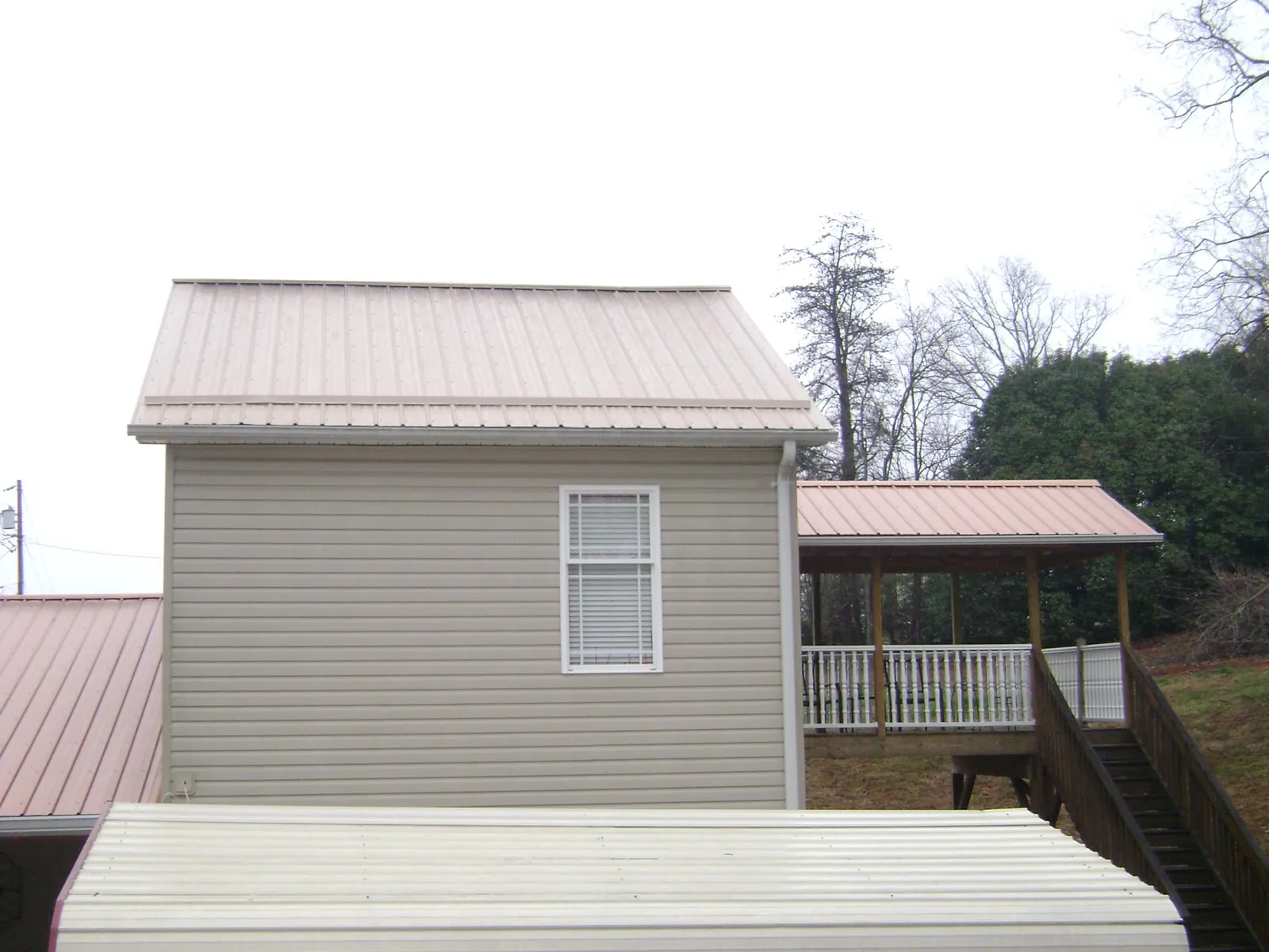 Tan metal roofs on a two story addition and attached porch, from a Roof Replacement job in Cuyahoga Falls