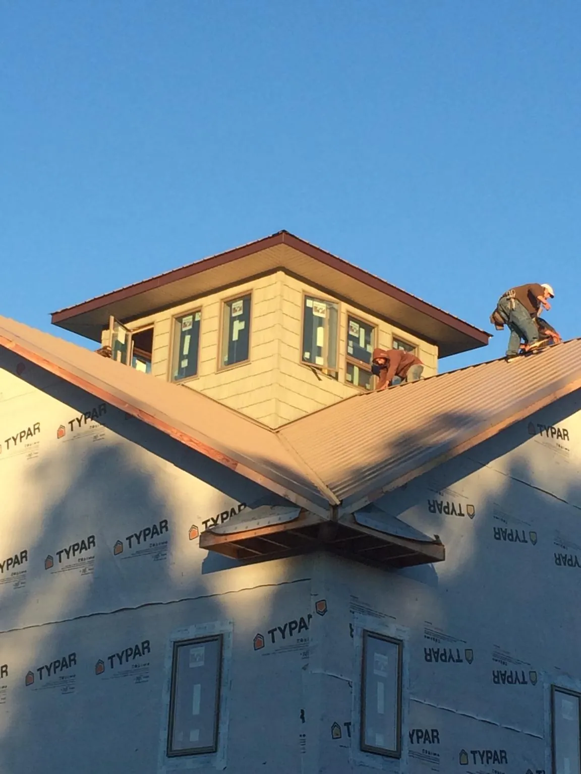 Roofers working around a rooftop cupola on a new metal roof at sunset — Roof Waterproofing in Cuyahoga Falls by Roofing Brothers